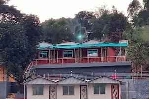 Un edificio de dos pisos con un balcón en el nivel superior y una estructura pequeña adosada con techo inclinado.