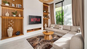 Ein modernes Wohnzimmer mit einer großen Couch, einem Couchtisch und einem an der Wand befestigten Fernseher.