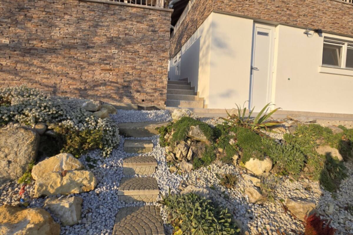 Una escalera de piedra que lleva a un edificio blanco con una puerta y ventanas.