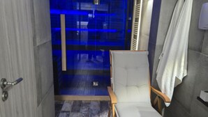 A narrow bathroom with a wooden chair, a towel rack, and a glass door leading to a shower area. - Villa Bella Vista (Ivanec)