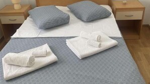 A neatly made bed with two pillows, a bedside table with a lamp, and a nightstand with a drawer. - Family House Kurtin by Brankica (Preko)