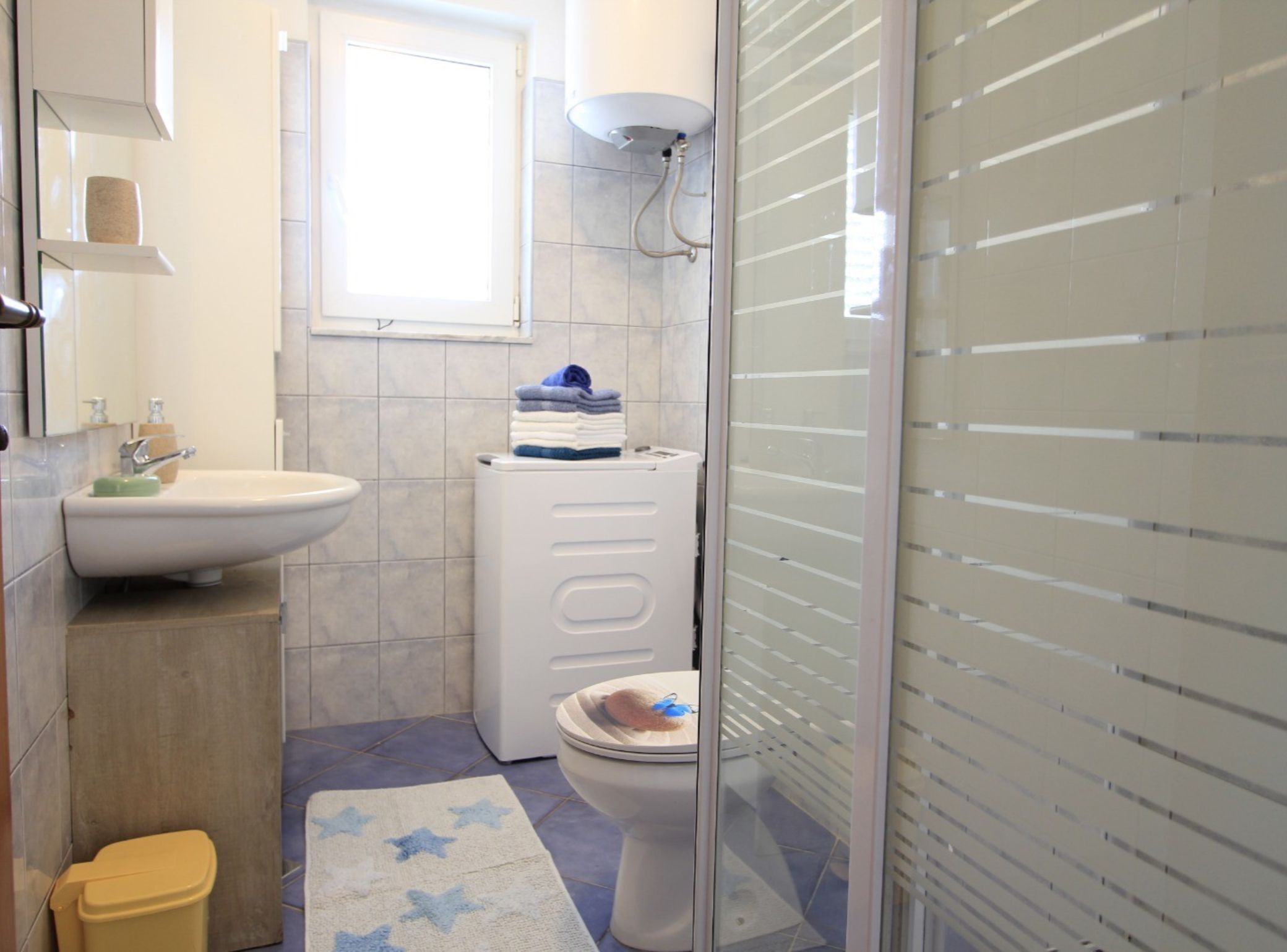 A compact bathroom with a sink, toilet, and a glass shower enclosure.
