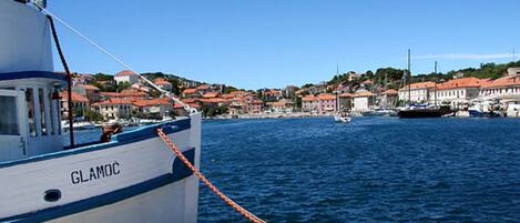 A boat named 'GLAMOC' docked at a harbor with buildings in the background.
