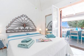 Une chambre d’hôtel avec un lit, un grand miroir, une table avec des chaises et une vue sur l’extérieur.