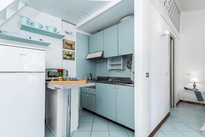 Una cocina con armarios azul claro, un refrigerador blanco y una encimera de madera con utensilios de cocina.