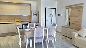 Eine moderne Küche mit Einbauofen, Kühlschrank und Essbereich mit Tisch für vier Personen.