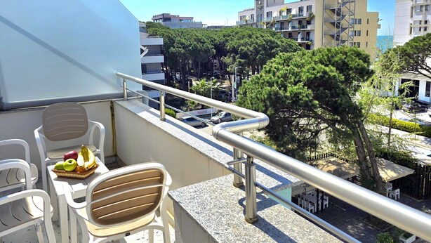Ein Balkon mit Sitzgelegenheit, einer Obstschale und Blick auf die umliegenden Gebäude und Bäume.