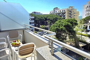 Ein Balkon mit Sitzgelegenheit, einer Obstschale und Blick auf die umliegenden Gebäude und Bäume.