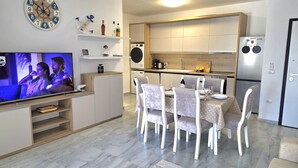 Eine moderne Küche mit Einbauofen, Kühlschrank und Essbereich mit Tisch und Stühlen.