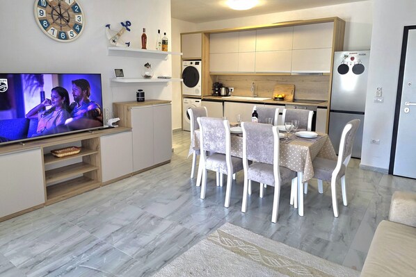 A modern kitchen with a built-in oven, a refrigerator, and a dining area with a table and chairs. - Holiday Apartment in Golem 070 (Golem)