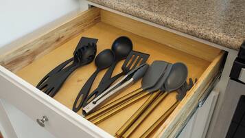 Uma gaveta com utensílios de cozinha, incluindo espátula, colher e concha.