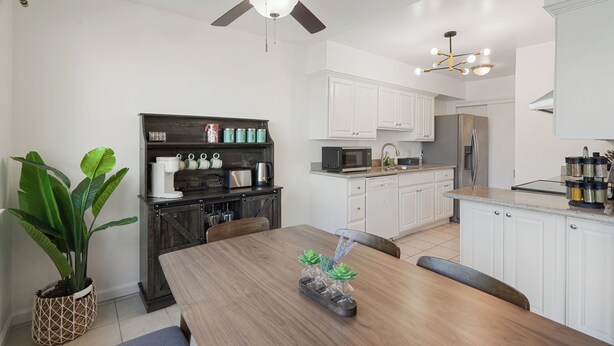 A modern kitchen with white cabinets, a dark wooden dining table, and a ceiling fan. - Lakefront Retreat  WaterViews 3BR 1.5BA  (San Mateo)