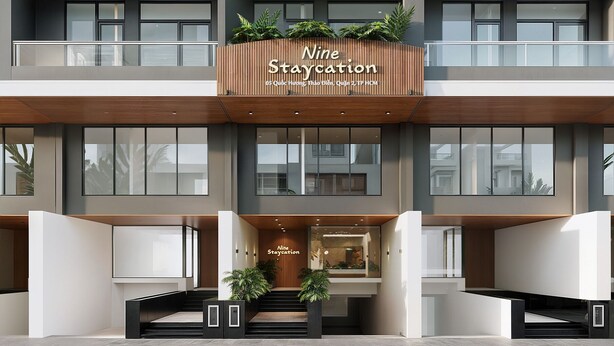 Een meerhoog hotel met balkons, grote ramen en een bord waarop staat 'Nine Staycation'.
