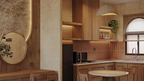 Een moderne keuken met houten kastjes, een inbouwmagnetron en een ronde houten tafel met stoelen.