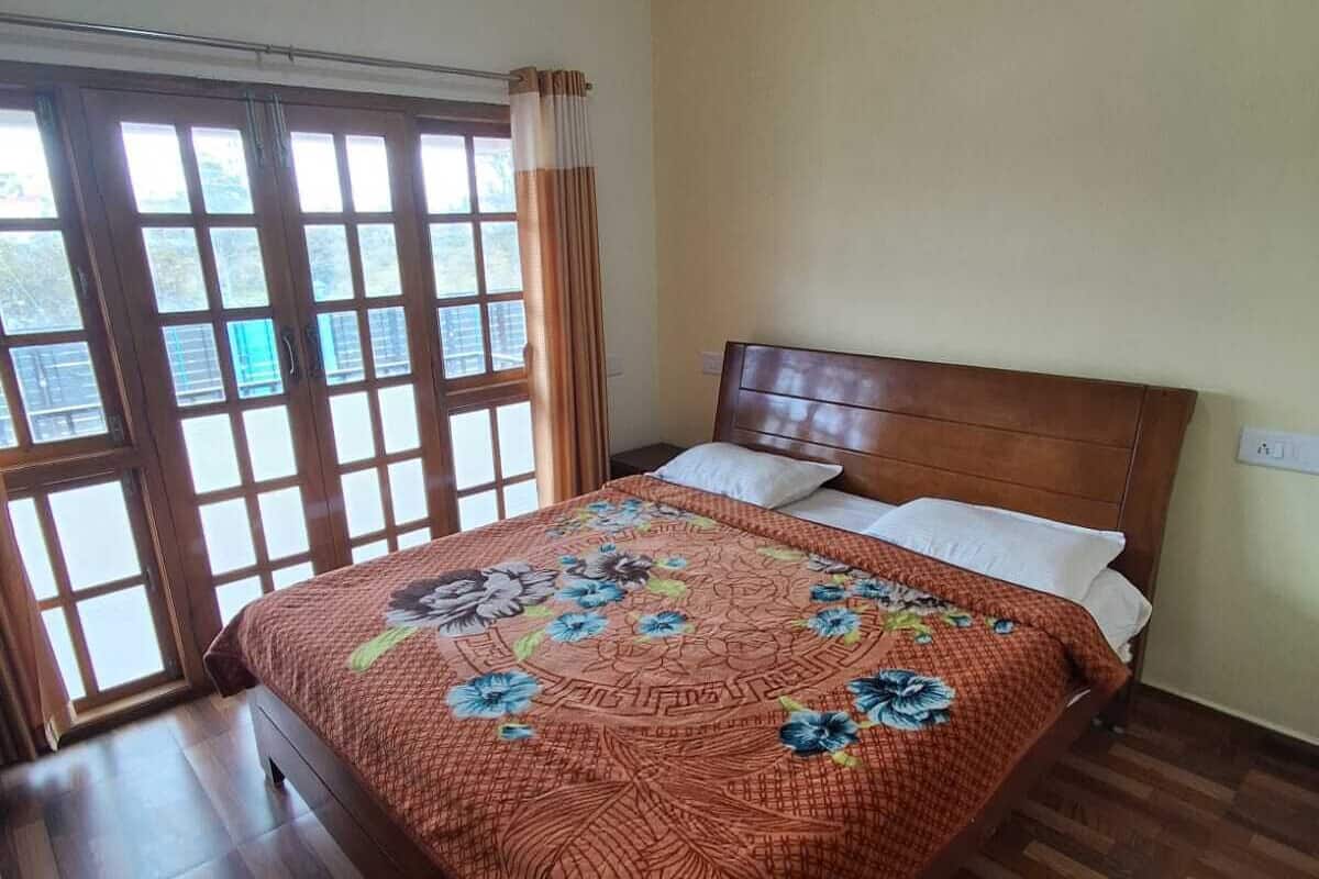 Ein Schlafzimmer mit einem hölzernen Bett, einem Fenster mit Vorhängen und Blick ins Freie.