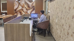 A hotel reception desk with a computer, a large marble wall, and a floral wallpapered wall. - Pacific Inn Paonta Sahib (Paonta Sahib)