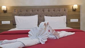 A hotel room with a tufted headboard, two white pillows, a red bedspread, and two wall-mounted lamps. - Pacific Inn Paonta Sahib (Paonta Sahib)