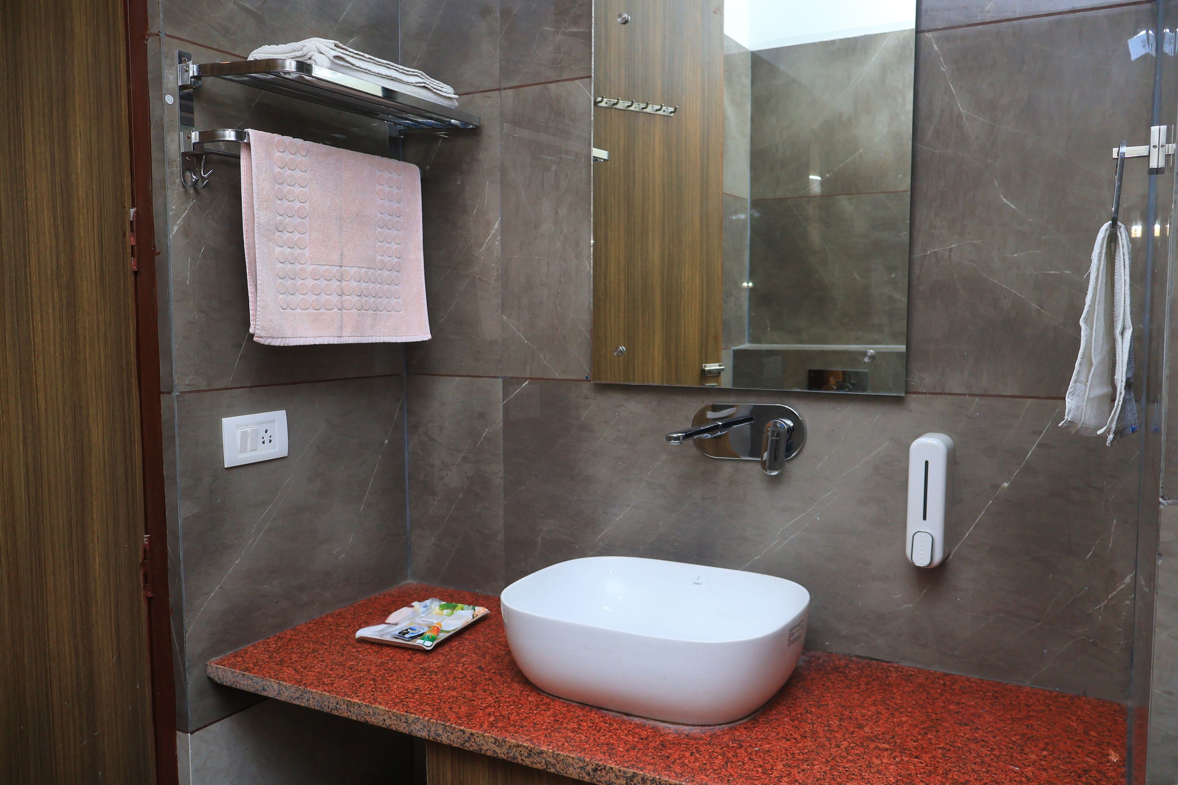 Une salle de bain avec un lavabo blanc, un miroir, un porte-serviettes et un distributeur de savon.