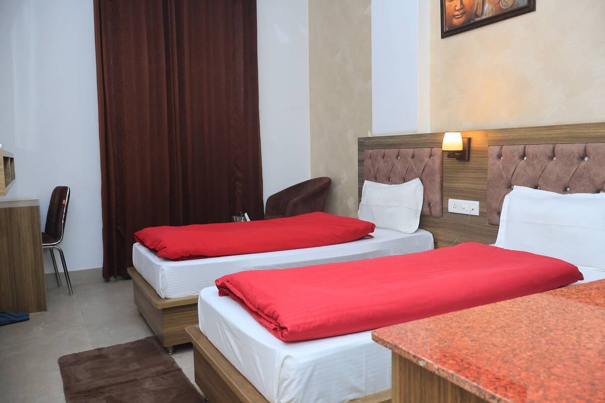 Une chambre d’hôtel avec deux lits, un bureau, une chaise et un tapis marron.