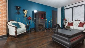 A living room with a fireplace, a white sofa, a wooden coffee table, and a blue accent wall.