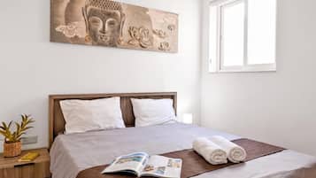 A neatly made bed with a brown bedspread, white pillows, and a magazine on the bed.
