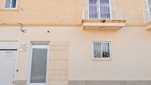 A building with a beige facade, a white door, and a balcony with white railings. - Sunny Bay View + shared pool Gozo (Xaghra)