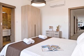 A hotel room with a bed, a bedside table with a magazine, a mirror, and a wardrobe. - Sunny Bay View + shared pool Gozo (Xaghra)