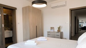 Ein Hotelzimmer mit einem großen Bett, einem Nachttisch mit Lampe, einem kleinen Schreibtisch und einer Wandklimaanlage.