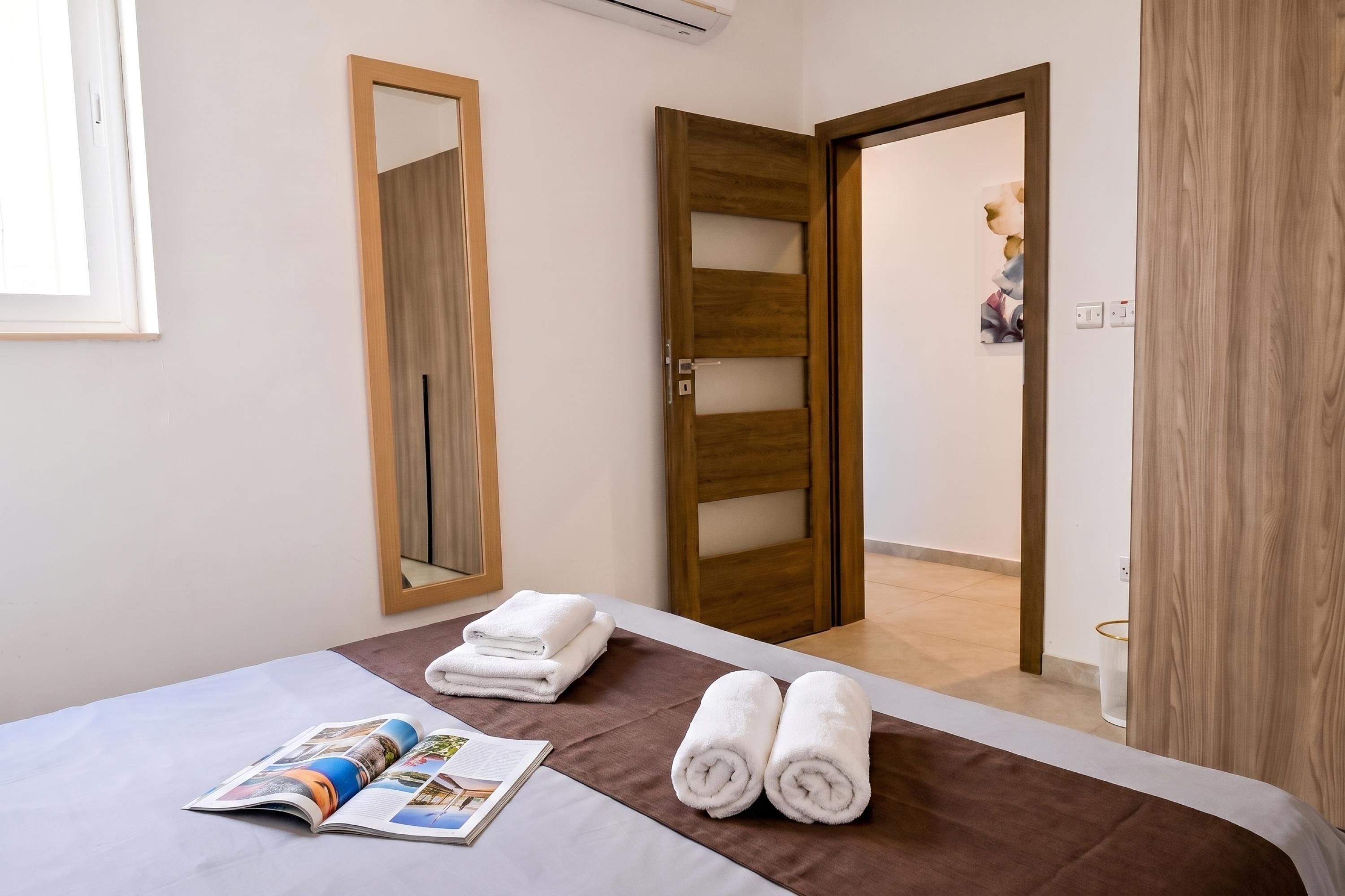 Une chambre d’hôtel avec un lit, un miroir, une porte et un porte-serviettes.