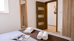 A hotel room with a bed, a mirror, a door, and a towel rack. - Sunny Bay View + shared pool Gozo (Xaghra)