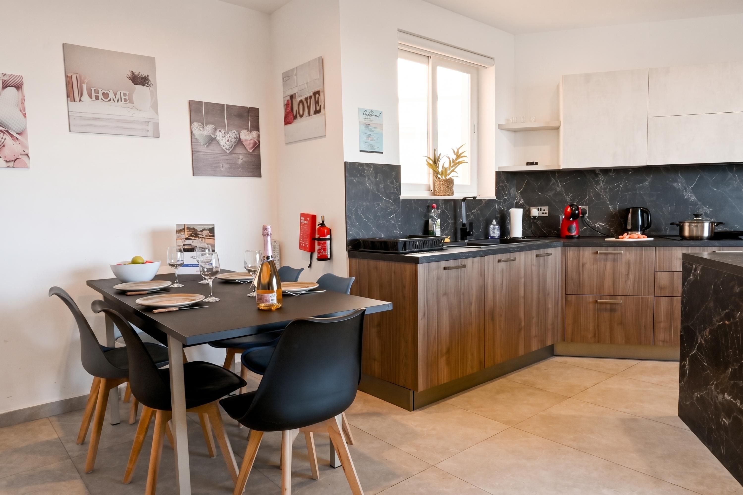 A modern kitchen with a central island, wooden cabinets, and a dining area with chairs and a table set for four.