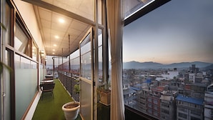 A balcony with a view of a cityscape and mountains. - Hotel De Universal (Kathmandu)
