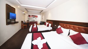 A hotel room with two beds, a desk, a chair, a television, and a kitchenette in the background. - Hotel De Universal (Kathmandu)