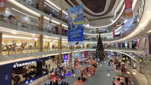 A multi-level shopping mall with a Starbucks on the lower level, a large Christmas tree in the center, and various shops and kiosks on the upper levels. - Gatotkaca Hotels (Surabaya)