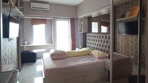 A modern hotel room with a large bed, a round table, and a TV. - Gatotkaca Hotels (Surabaya)