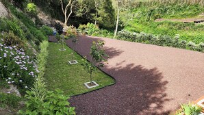 A landscaped garden with a gravel path, young trees, and flowering plants.