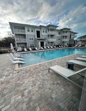 A swimming pool with lounge chairs and a multi-story building in the background. - Charming Cozy 2-bedroom apartment in Jacksonville Florida (Jacksonville)