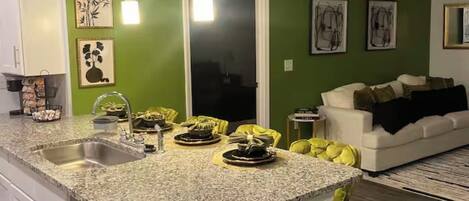 A kitchen with a granite countertop, white cabinets, and a green accent wall.