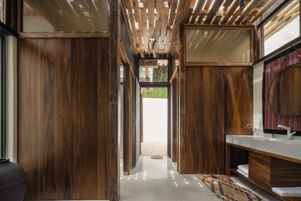A modern bathroom with wooden paneling, a large mirror, and a white sink.
