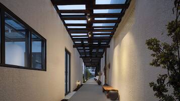 A corridor with a wooden ceiling, a bench, and a potted plant.