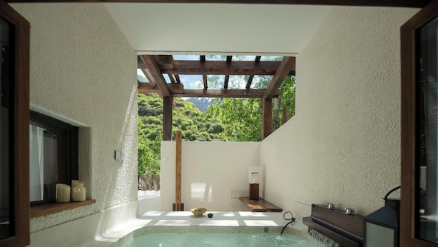 A spa area with a hot tub, wooden beams, and a view of lush greenery. - EGO Hot Spring Resort Hotel (Garze)