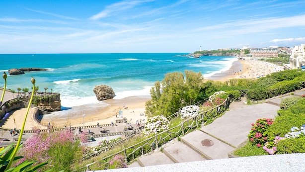 Ein Küstenblick mit Strand, Leuchtturm und einer Promenade mit Stufen zum Strand hinab.