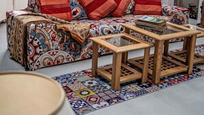 Een kamer met een zithoek, een houten bijzettafeltje en een kamerbreed tapijt.