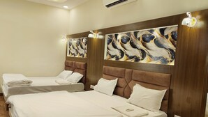 A hotel room with two beds, wooden headboards, and abstract wall art. - Pink Mahal Hotel And Resort (Amer)