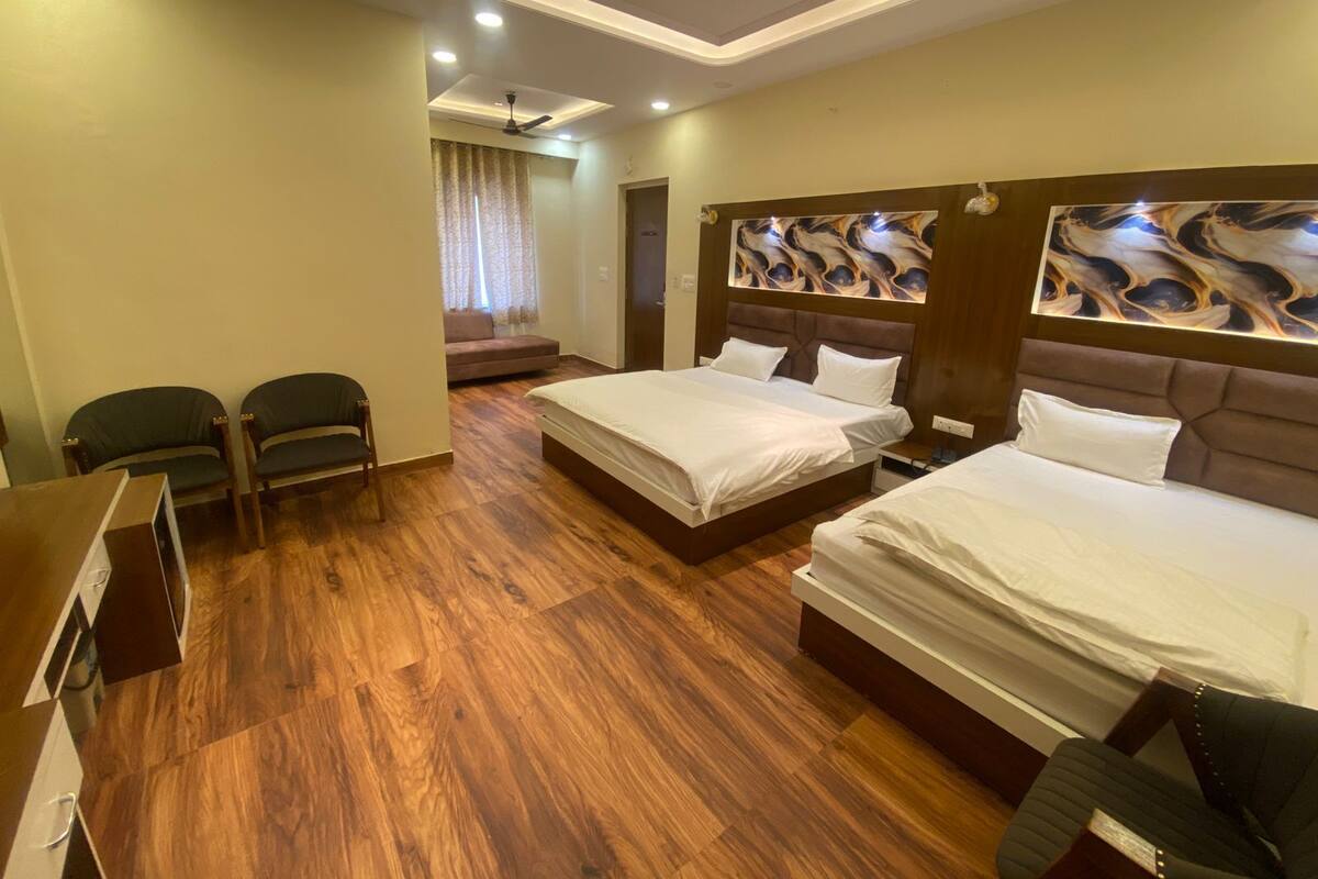 A hotel room with two beds, a desk, a chair, and a ceiling fan.