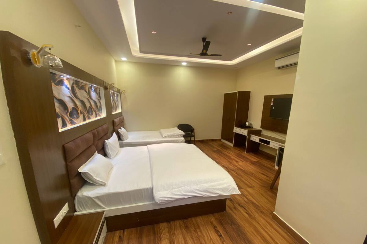 A hotel room with a large bed, a desk, a chair, and a TV.