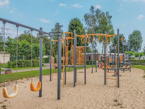Ein Spielplatz mit Schaukeln, Reckstange und Sandkasten.