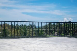 A balcony with a metal railing, a concrete floor, and a view of palm trees and a clear sky. - Nilaveli Royal Paradise (Nilaveli)
