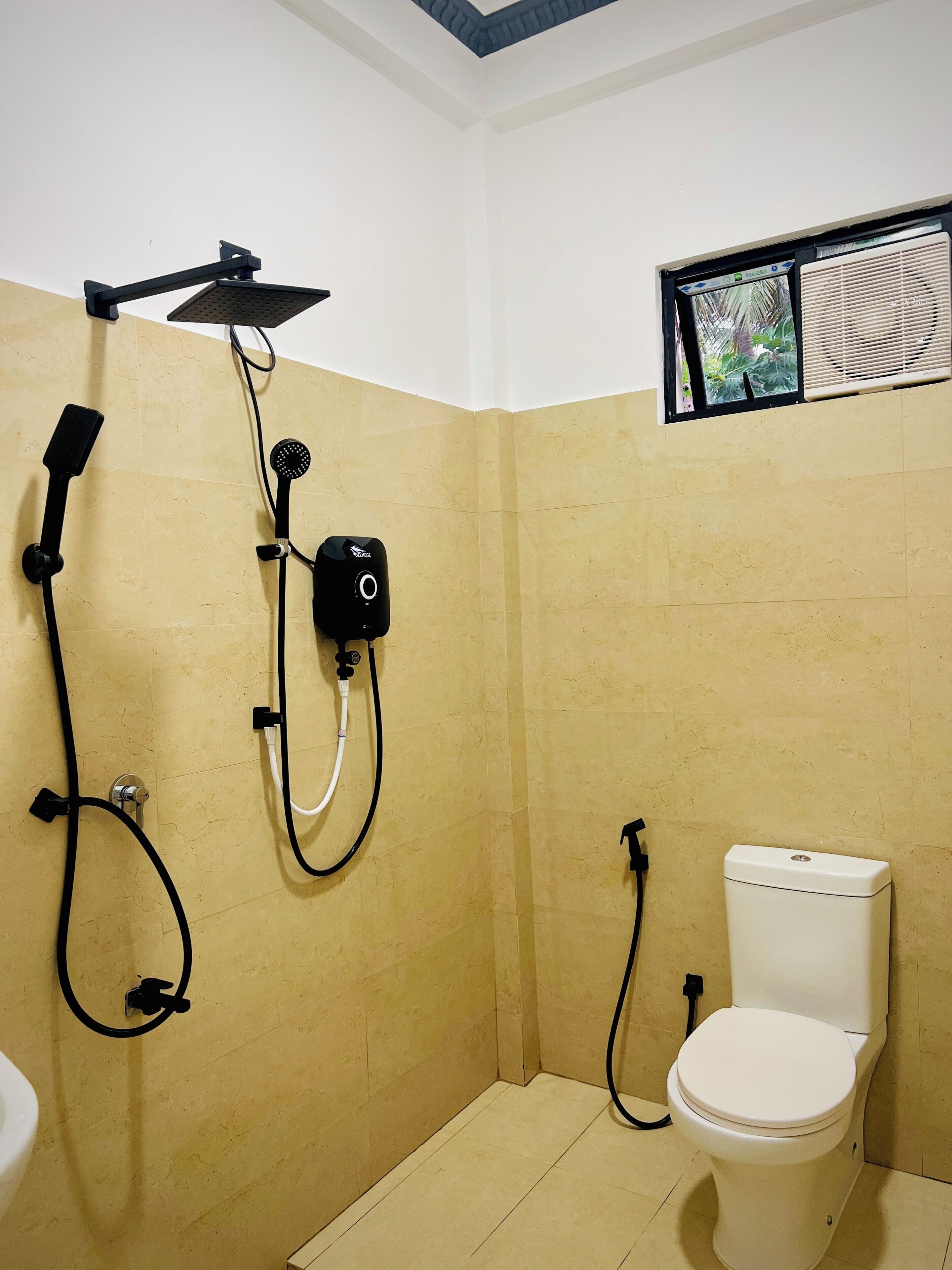 Un baño con ducha, inodoro y ventana con vistas.