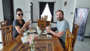 Egy étkező, ahol egy két személyre megterített asztal, egy virágváz és egy, a szolgáltatásokat hirdető transzparens található.